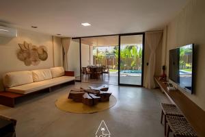 ein Wohnzimmer mit Sofa und Tisch in der Unterkunft Casa Karoá, a Beira-Mar na Rota dos Milagres, Praia de Marceneiro in Barra do Camaragibe