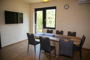 une salle à manger avec une table, des chaises et une horloge dans l'établissement AKZ Apartman, à Makó