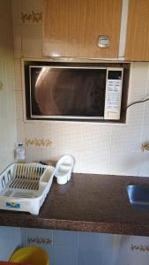 a kitchen with a microwave and a counter top at Casa com piscina para até 6 pessoas com duas camas de casal e sofá-cama casal in Serra Negra