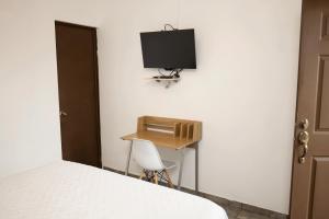 a bedroom with a desk and a television on the wall at Hotel Jardin De Las Marias in Suchitoto