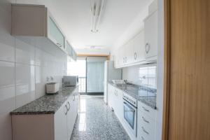 cocina con armarios blancos y encimeras de granito en Porto RiverSea Quay Apartment, en Matosinhos