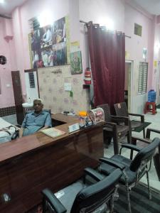 a man sitting at a table in a room with chairs at Bhardwaj Home Stay in Mathura