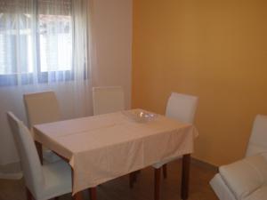 uma mesa de jantar com cadeiras brancas e uma toalha de mesa branca em Apartment MS em Pula