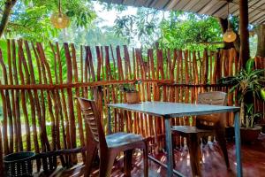 una mesa y sillas frente a una valla de bambú en Gajaa Corido Safari Homestay, en Udawalawe