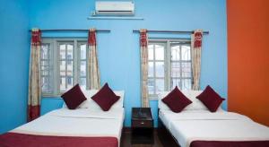 two beds in a room with blue walls and windows at OYO 381 Hotel Pashupati Plaza in Kathmandu +91 photos