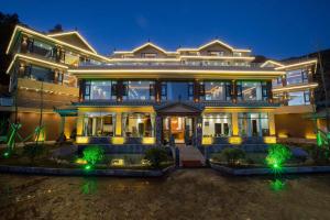 a large house with lights in front of it at Lugu Lake Yunshang Holiday Hotel in Zuosuo