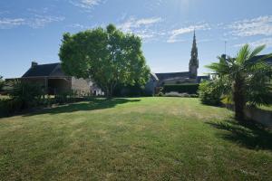 a church with a tree and a grass yard at La petite maison in Monthault +12 photos
