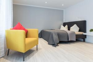 a bedroom with a bed and a yellow chair at Boutique Apartments am Stadtgarten in Freiburg im Breisgau