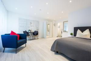 a bedroom with a bed and a blue chair and a table at Boutique Apartments am Stadtgarten in Freiburg im Breisgau
