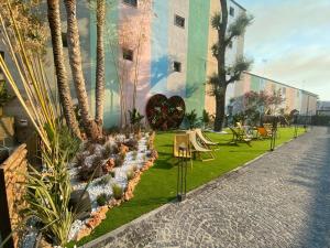 a garden with palm trees and chairs and a building at Paradisea club and residences in Volla