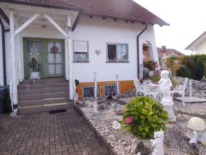 Casa blanca con porche delantero y sillas en Gästehaus Baur, en Kappel-Grafenhausen