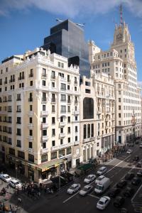 Un gran edificio blanco con coches aparcados en un estacionamiento. en Petit Palace Triball, en Madrid
