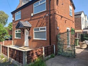 a brick house with a gate and a fence at Cosy 2-Bed House in Manchester in Manchester