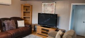 a living room with a couch and a flat screen tv at Cosy Cottage in Harvington in Harvington