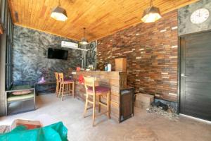 a room with a bar with chairs and a brick wall at OYO 75374 Baan Rak Mai in Kanchanaburi