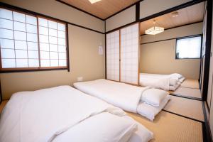 a room with three beds and two windows at 夏様楽善 Historic Kyoto Machiya,Experience Japanese Lifestyle Comfortably in Kyoto