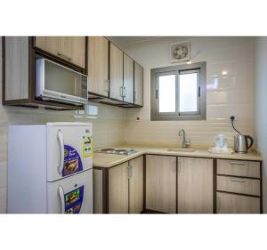 a kitchen with a white refrigerator and a microwave at Sunday Pearl Suites Formerly Al Louloah Al Baraqah Apartments in Jeddah +17 photos
