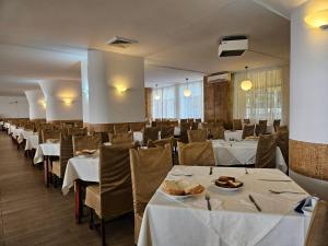a dining room with white tables and chairs at Hotel Mures in Baile Felix
