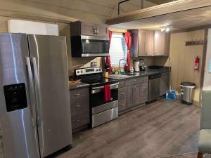 a kitchen with a stainless steel refrigerator and cabinets at The Big Tiny White House in Hurricane