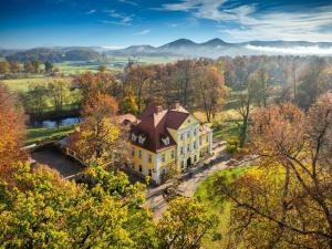 an aerial view of a large yellow house with a brown roof at Pałac Łomnica - Karkonosze / Riesengebirge in Jelenia Góra