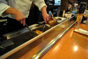 a chef in a kitchen preparing food with utensils at City Park Hotel Hachinohe in Minatomachi