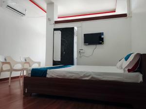 a bedroom with a bed and a tv on the wall at Village Lodge in Udalguri