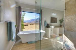 a bathroom with a tub and a glass shower at Giantscup Wilderness Reserve in Underberg +57 photos