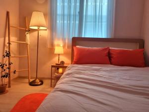 a bedroom with a bed with red pillows and a window at Ye Stay in Daegu