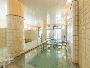 a large swimming pool in a building with columns at Ryokan Yasuda-Onsen Yasuragi Agano in Agano