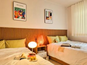 a bedroom with two beds and a table with a lamp at Ye Stay in Daegu
