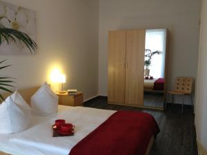 sypialnia z łóżkiem z czerwonymi kubkami i lustrem w obiekcie Apartmenthaus Feuerbach w Lipsku