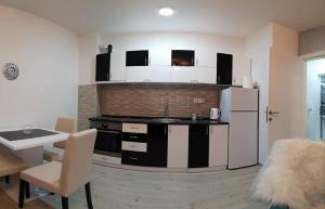 a kitchen with a white refrigerator and a table at SILVER aPARTMAN 1 in Sremska Mitrovica