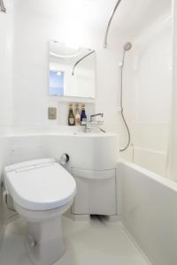 a white bathroom with a toilet and a bath tub at HOTEL MYSTAYS Shin Osaka Conference Center in Osaka