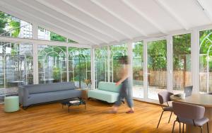 eine Person, die durch ein Wohnzimmer mit Fenstern geht in der Unterkunft Limehome Berlin Weserstraße, Friedrichshain in Berlin