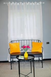a bench with yellow pillows and a vase on a table at Richs Crib - Puerto Galera Affordable House in Puerto Galera