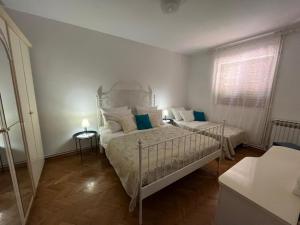 a white bedroom with a bed and a window at Apartment with swimming pool in Jelsa