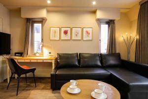 a living room with a black leather couch and a table at the Moto Hotel Shinjuku in Tokyo