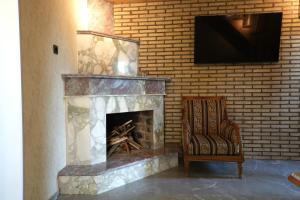 a fireplace with a chair and a television on a brick wall at ILIAS Guest House in Kvareli