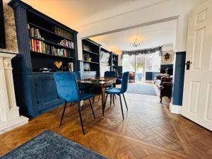 a dining room with a table and blue chairs at 4 Bedroom House - Hot Tub - BBQ - Beach - Garden - Cinema - Parking in Southbourne