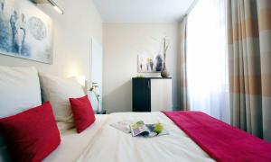 a bedroom with a bed with red pillows and a book at Apartmenthotel Quartier M in Leipzig