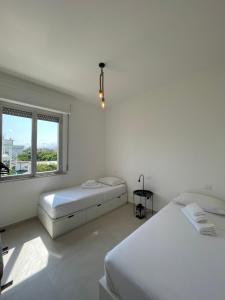 a white bedroom with two beds and a window at La Perla Saba 2 in Montemarciano
