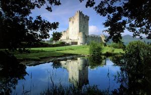 un castillo con su reflejo en un estanque en Copper Kettle B&B, en Killarney