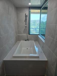 a bathroom with a white tub and a window at Sacheon Zambo Hotel in Sacheon