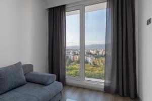 a living room with a couch and a large window at Cevahir Sky City 2BR Family APT, Fitness & Spa in Skopje