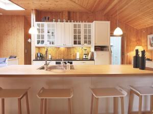 Una cocina con gabinetes blancos y una encimera con taburetes. en 6 person holiday home in Gilleleje, en Gilleleje