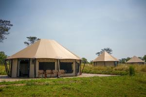 a tent with chairs in it in a field at Malaika Ndutu Luxury Camp in Sinoni