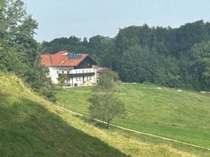 a house on top of a grassy hill with trees at Traumpanorama zwischen Chiemsee und Salzburg - 74 qm - mit E-Ladesäule in Surberg