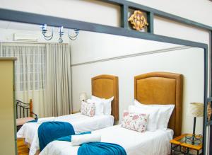 two beds in a hotel room with white sheets at Cecil John Rhodes Guest house in Kimberley