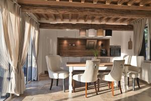 a kitchen with a wooden table and white chairs at Le Jardin des Hespérides - Piscine intérieure, Jacuzzi et Sauna in Fourmetot