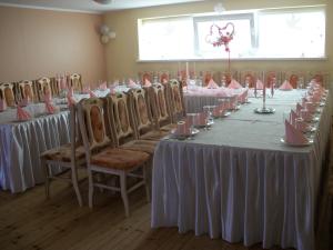 a row of tables in a room with white tablecloths at Apartamentai in Mažonai